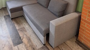 Un canapé modulable avec une méridienne, des murs verts et un mur d’accent en briques.