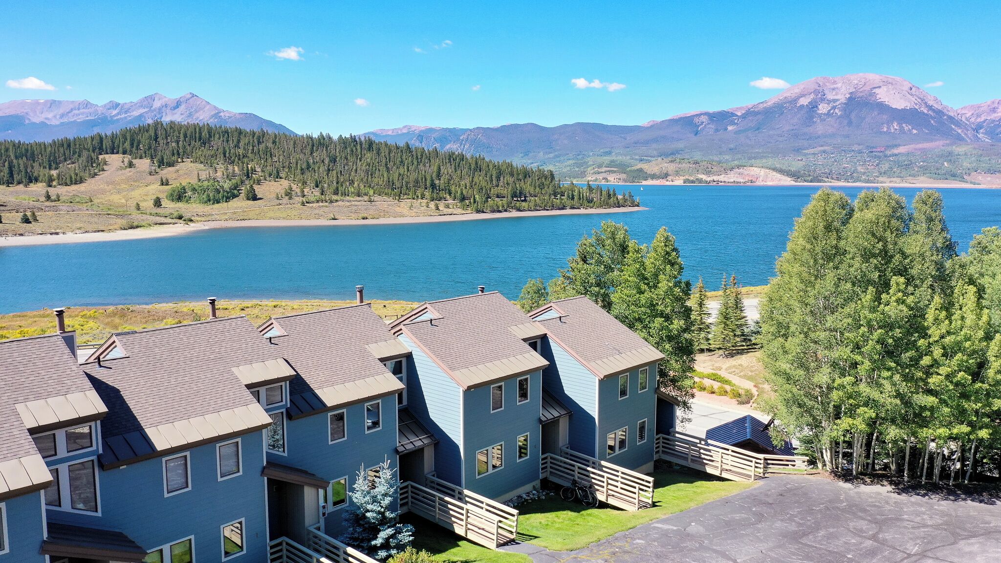 A residential area with multiple houses, a clear view of a lake, and mountains in the background.