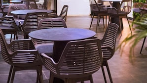 A bar area with tables and chairs, a television screen, and a variety of bottles on shelves. - Saint Tropez Hotel and Suites (Abuja)