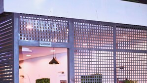 A restaurant with a modern design, featuring a glass entrance, outdoor seating, and a decorative metal fence. - Saint Tropez Hotel and Suites (Abuja)