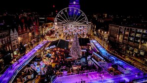 A bustling nighttime cityscape with a prominent Ferris wheel, a large illuminated Christmas tree, and a skating rink. - Market Street Apartment 3A Flat 1 (Nottingham)