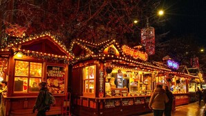 A nighttime market with illuminated stalls, including a hot roast coffee shop and a food vendor selling Mexican chicken and pulled pork fries. - Market Street Apartment 3A Flat 1 (Nottingham)
