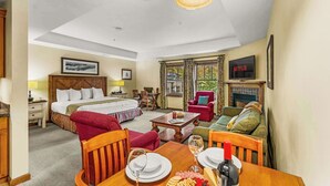A hotel room with a bed, a dining table set with plates and wine glasses, a TV, and a fireplace. - NEW LISTING | Studio at Mountaineer Square, Lifts 2 min Walk (Crested Butte)