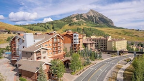 A mountain resort with multi-story buildings, a road, and a bridge. - NEW LISTING | Studio at Mountaineer Square, Lifts 2 min Walk (Crested Butte)