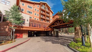 A multi-story building with a wooden facade, a covered entrance, and a landscaped area with trees and a pathway. - NEW LISTING | Studio at Mountaineer Square, Lifts 2 min Walk (Crested Butte)