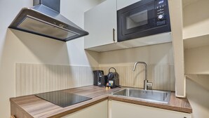 A compact kitchen with a microwave, stove, and sink. - Charmant Studio Duplex Beaubourg Le Marais (Paris)