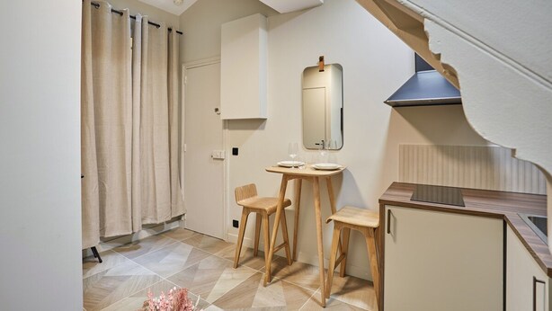 A compact kitchen with a skylight, wooden stools, a small table, and a cabinet. - Charmant Studio Duplex Beaubourg Le Marais (Paris)