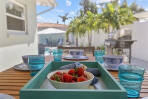 A table with a tray containing a bowl of strawberries, blue glass cups, and a white bowl with a blue pattern. - Private Heated Pool | Walk to IRB Beach (Indian Rocks Beach)