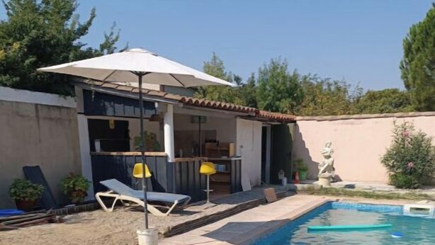 Piscina com deck revestido, área de varanda coberta com cadeiras e uma estátua.