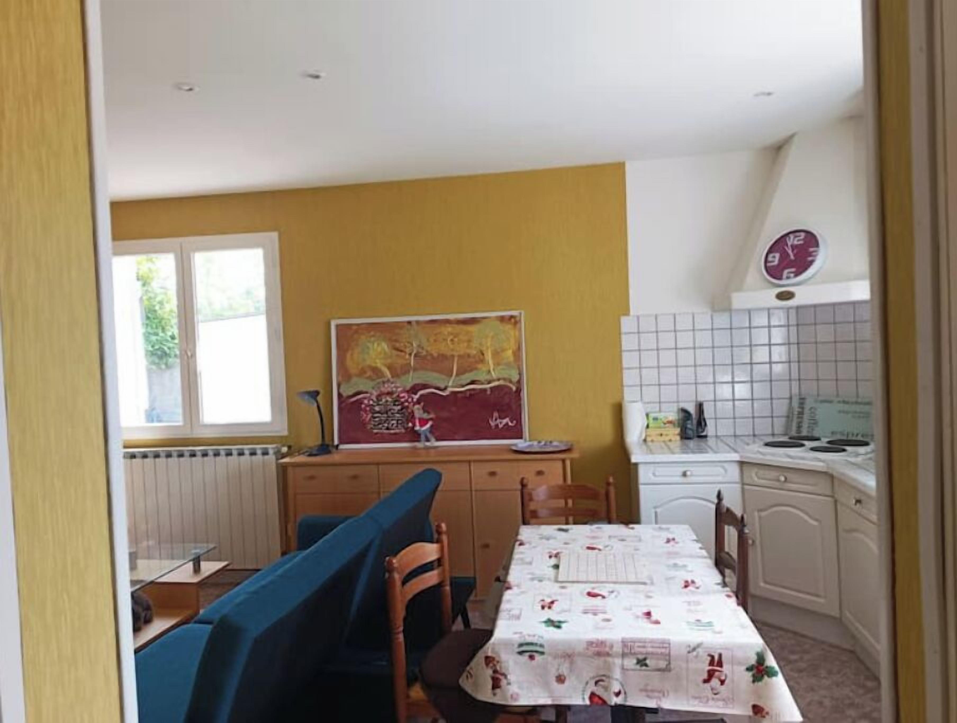 A compact kitchen with a dining area, a window, and a wall-mounted clock.