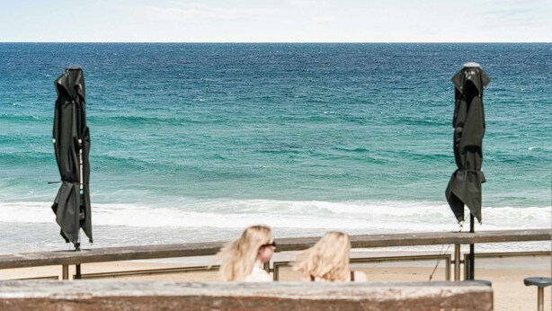 Vista de la playa con una barandilla y dos sombrillas negras.