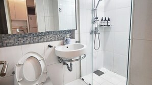 A modern bathroom with a toilet, sink, and glass-enclosed shower.