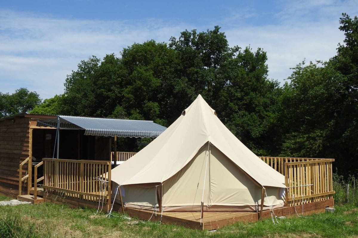 A tent with a wooden deck and a small cabin with a metal roof.