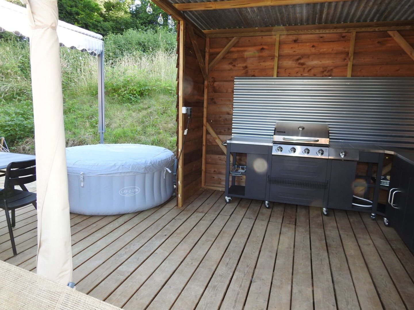 An outdoor patio with a grill, a hot tub, and a wooden deck.