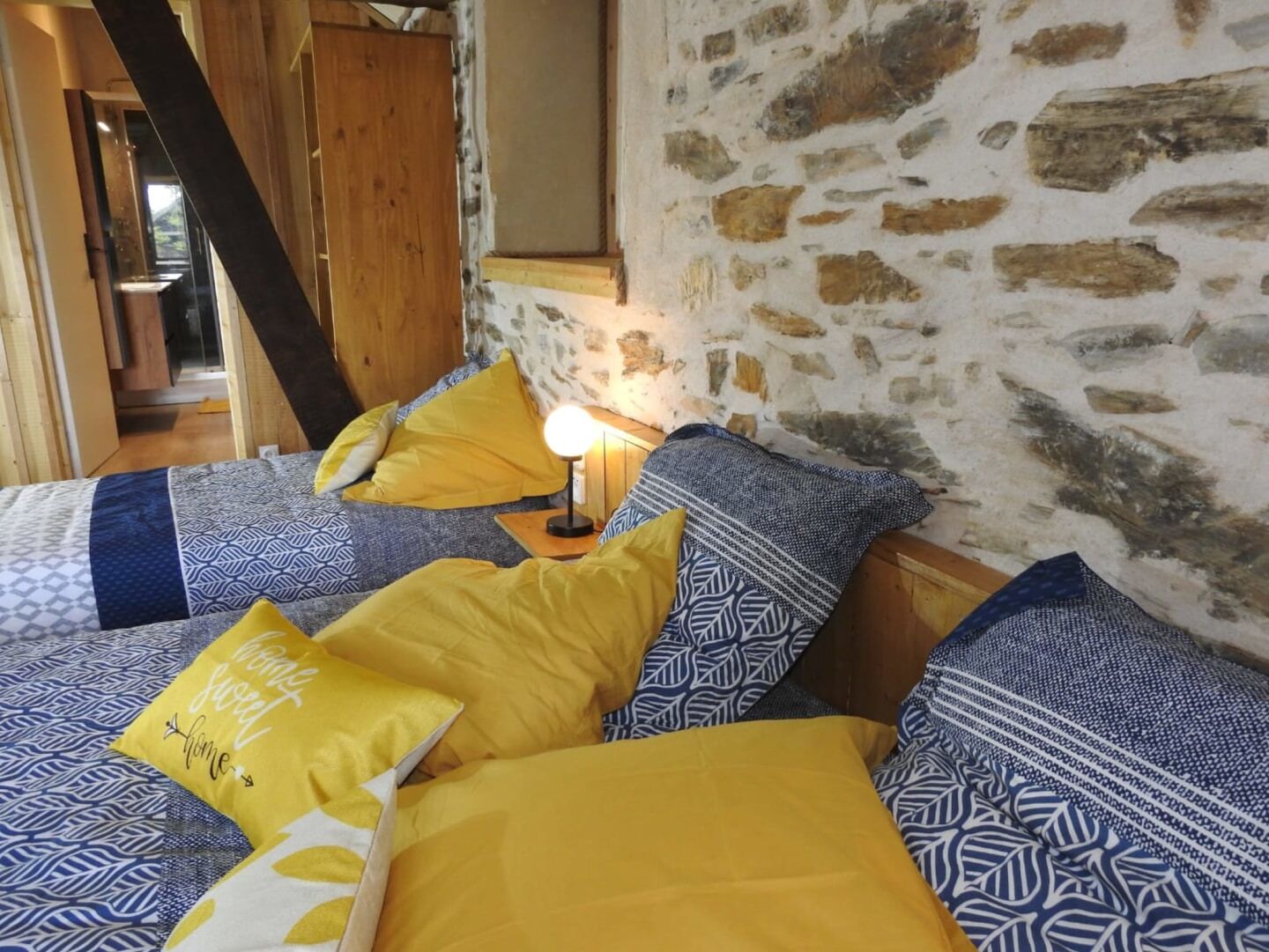 Un dormitorio acogedor con pared de piedra, estructura de cama de madera y ropa de cama estampada.