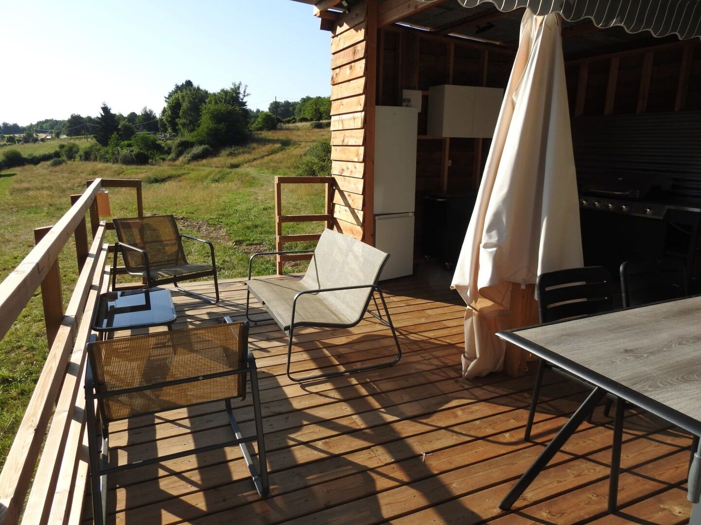 Une terrasse extérieure avec une table et des chaises, un espace barbecue et une vue sur le paysage environnant.
