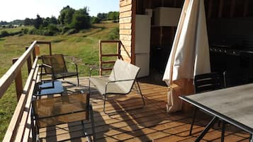 Une terrasse extérieure avec une table et des chaises, un espace barbecue et une vue sur le paysage environnant.