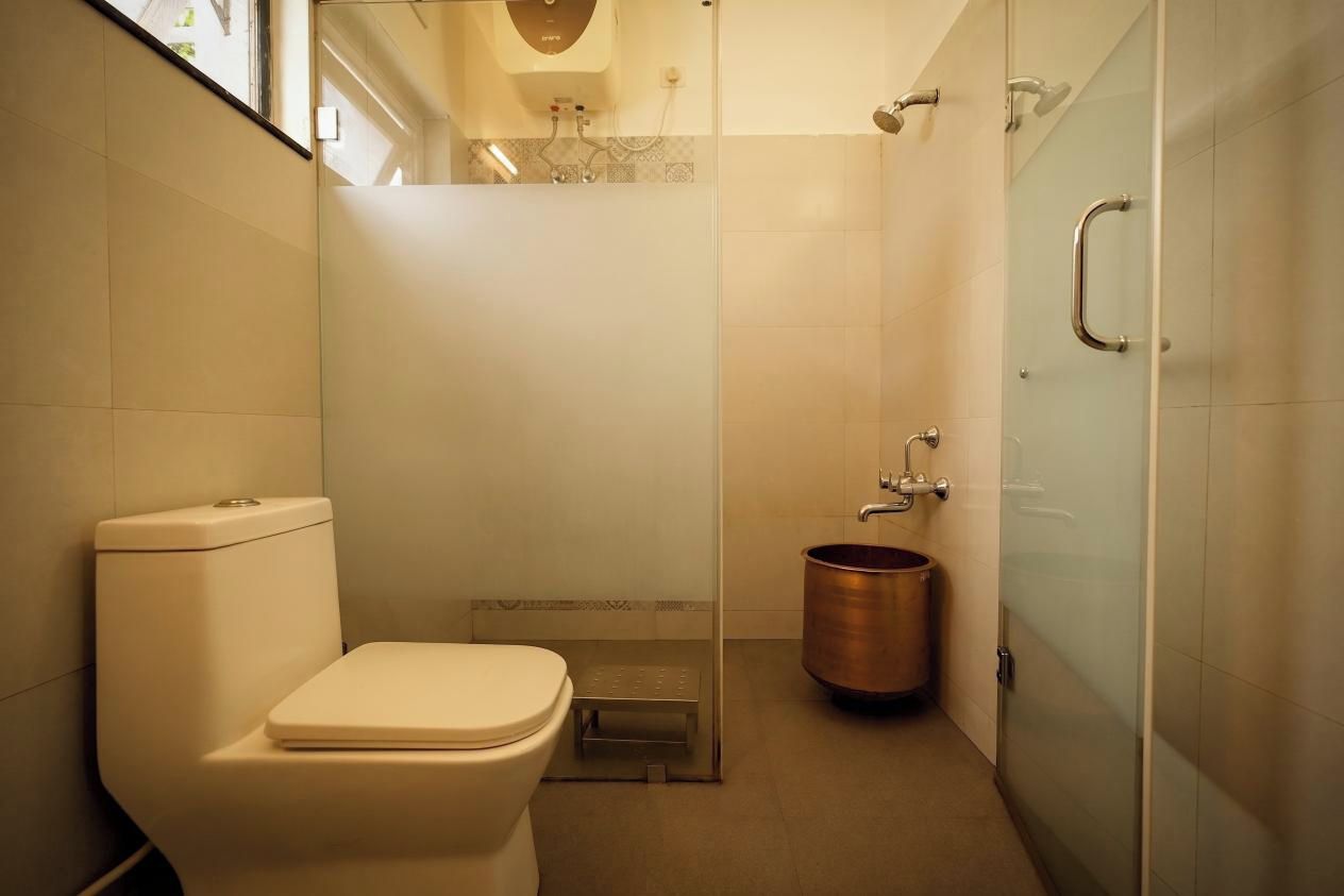 A modern bathroom with a toilet, a shower enclosure, and a copper bucket.