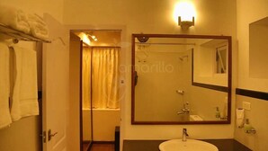 A hotel bathroom with a large mirror, a sink, and a shower area. - The Tamarillo (Ooty)