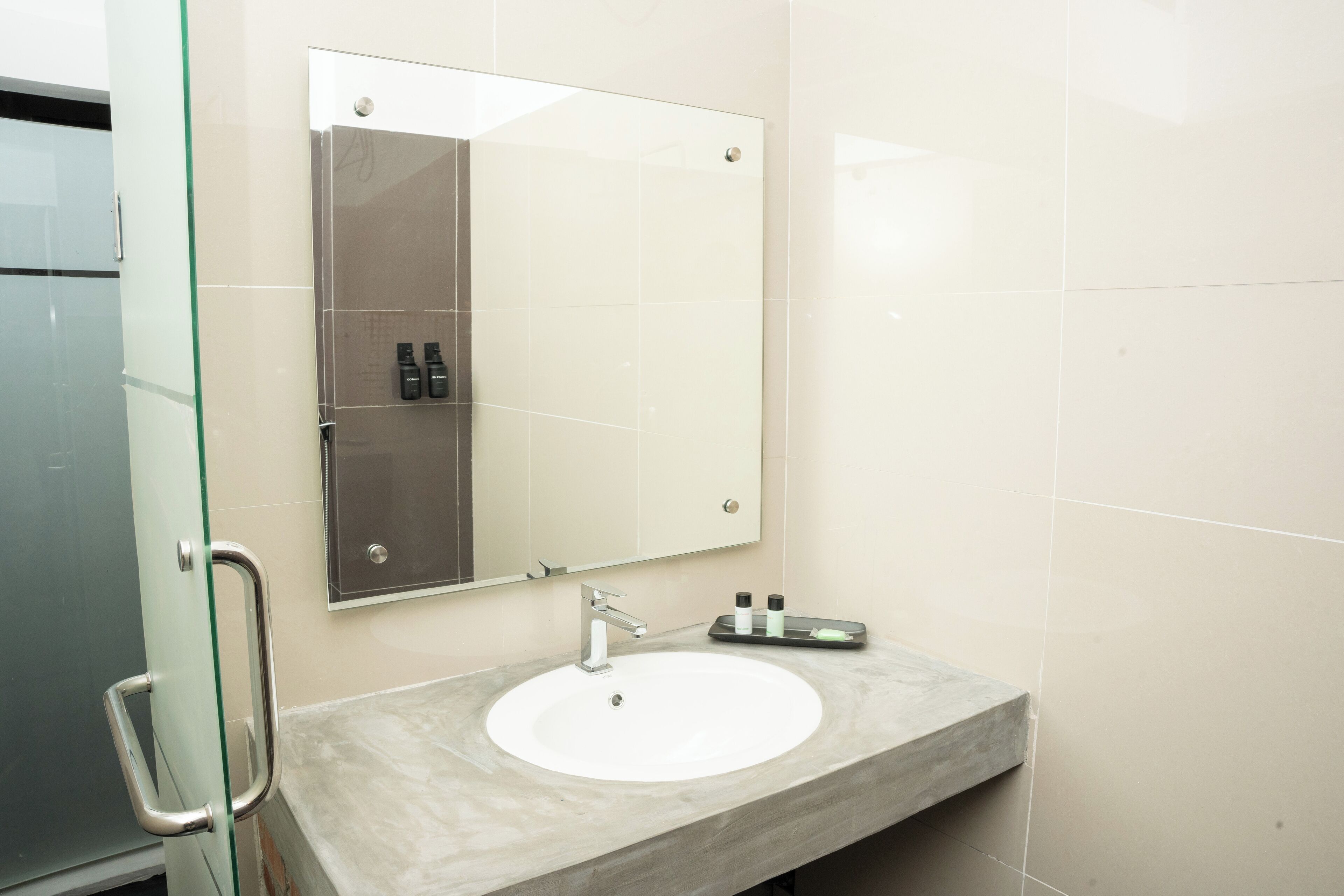 A bathroom with a white sink, a mirror, and a glass partition.