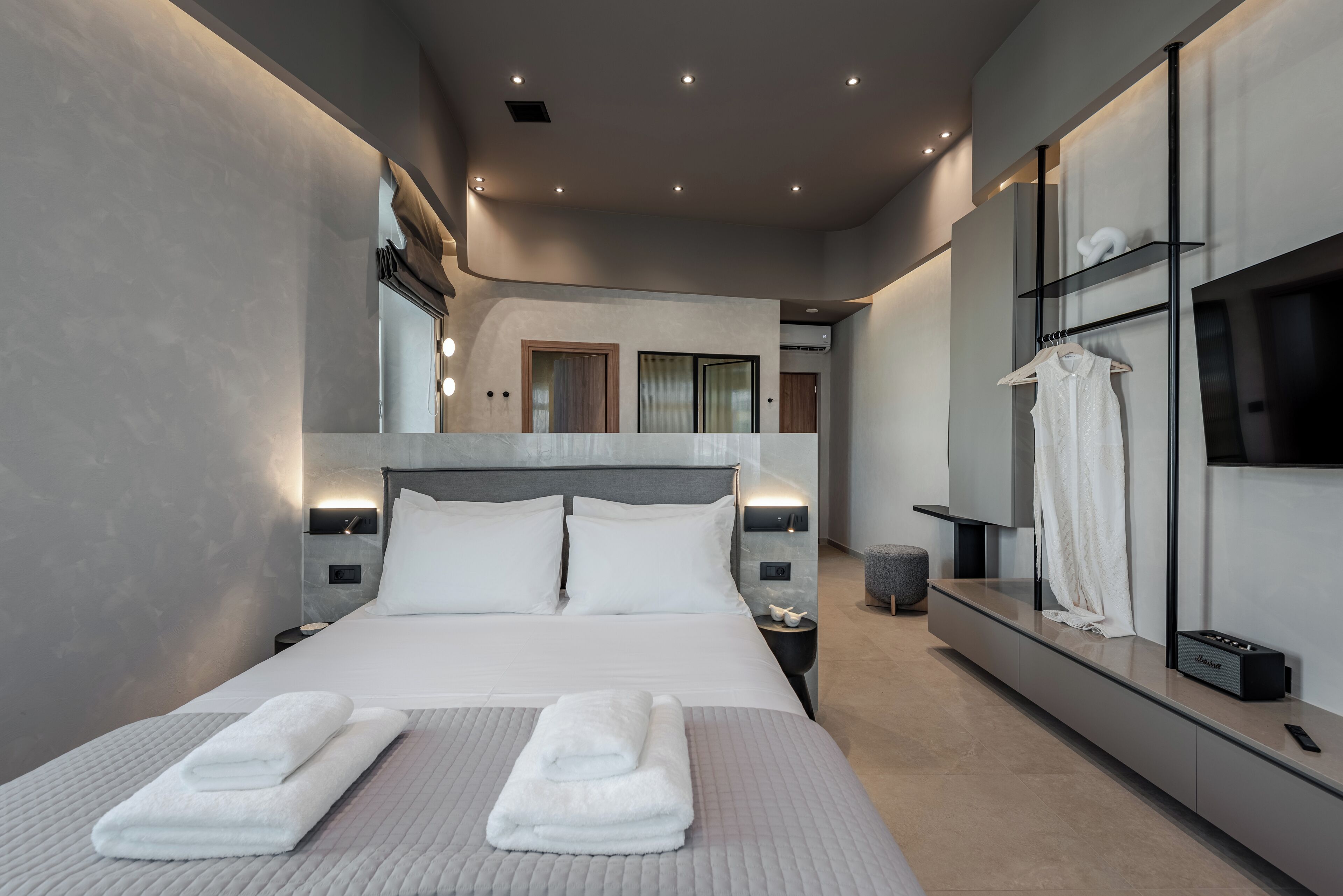 A modern hotel room with a large bed, bedside tables, a TV, and a wardrobe.
