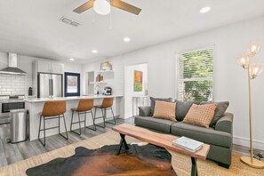 A modern kitchen with a central island, bar stools, and a dining area.