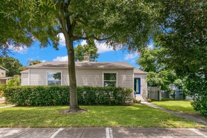 A single-story house with a front yard, a tree, and a blue door.