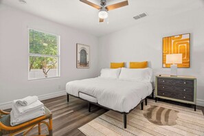 A bedroom with a bed, a nightstand, a chair, and a window with blinds.