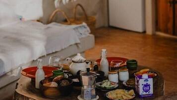 Une pièce chaleureuse avec une table en bois rustique, dressée avec divers aliments, et un petit réfrigérateur.