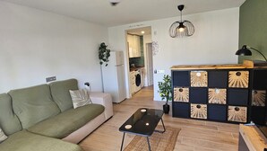 Ein modernes Wohnzimmer mit einem grünen Sofa, einem schwarzen Couchtisch und einem Deckenventilator.