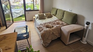 A bedroom with a bed, a sofa, a table, and a heater. - Oasis Duna Ground floor, Pool facing newly refurbished apartment, Corralejo (la Oliva)