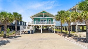 A beachfront property with a central building featuring a balcony and a covered walkway.