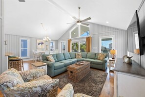 A spacious living room with a sectional sofa, a dining area, and a ceiling fan. - Beach House | Private Pool | 1 Min Walk to Beach | Sleeps 11 (Gulf Shores)