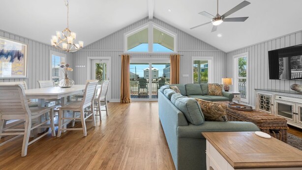 A spacious living area with a dining table, chairs, a sofa, and a television.
