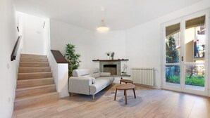 Ett modernt vardagsrum med en trappa, en öppen spis, en soffa och ett matbord.