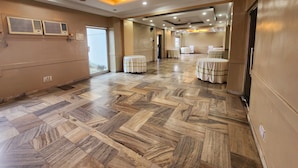 A spacious hotel lobby with a patterned floor, ceiling fans, and recessed lighting.