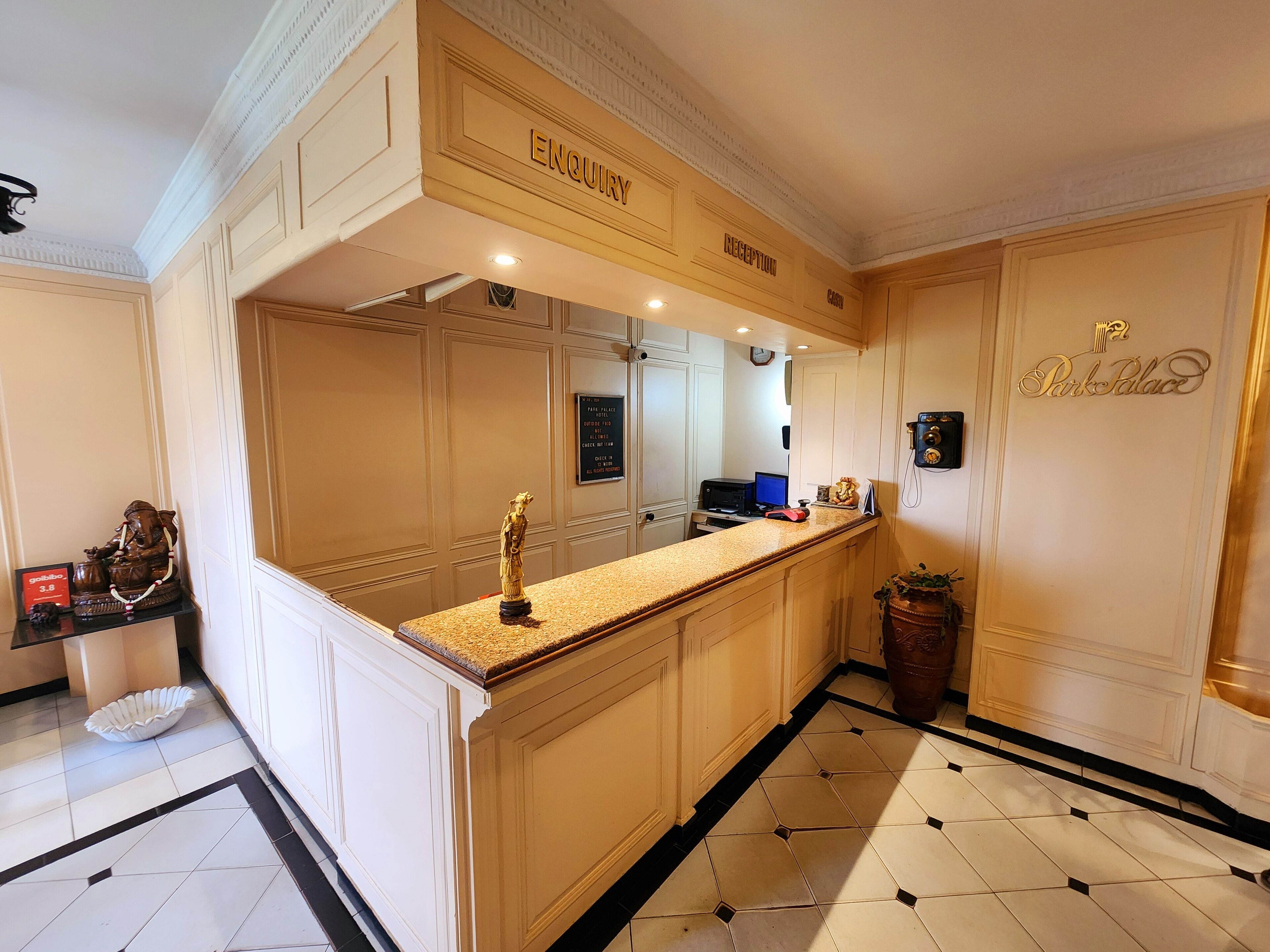 A hotel reception area with a reception desk, a clock, and a sign that reads 'Enquiry.'