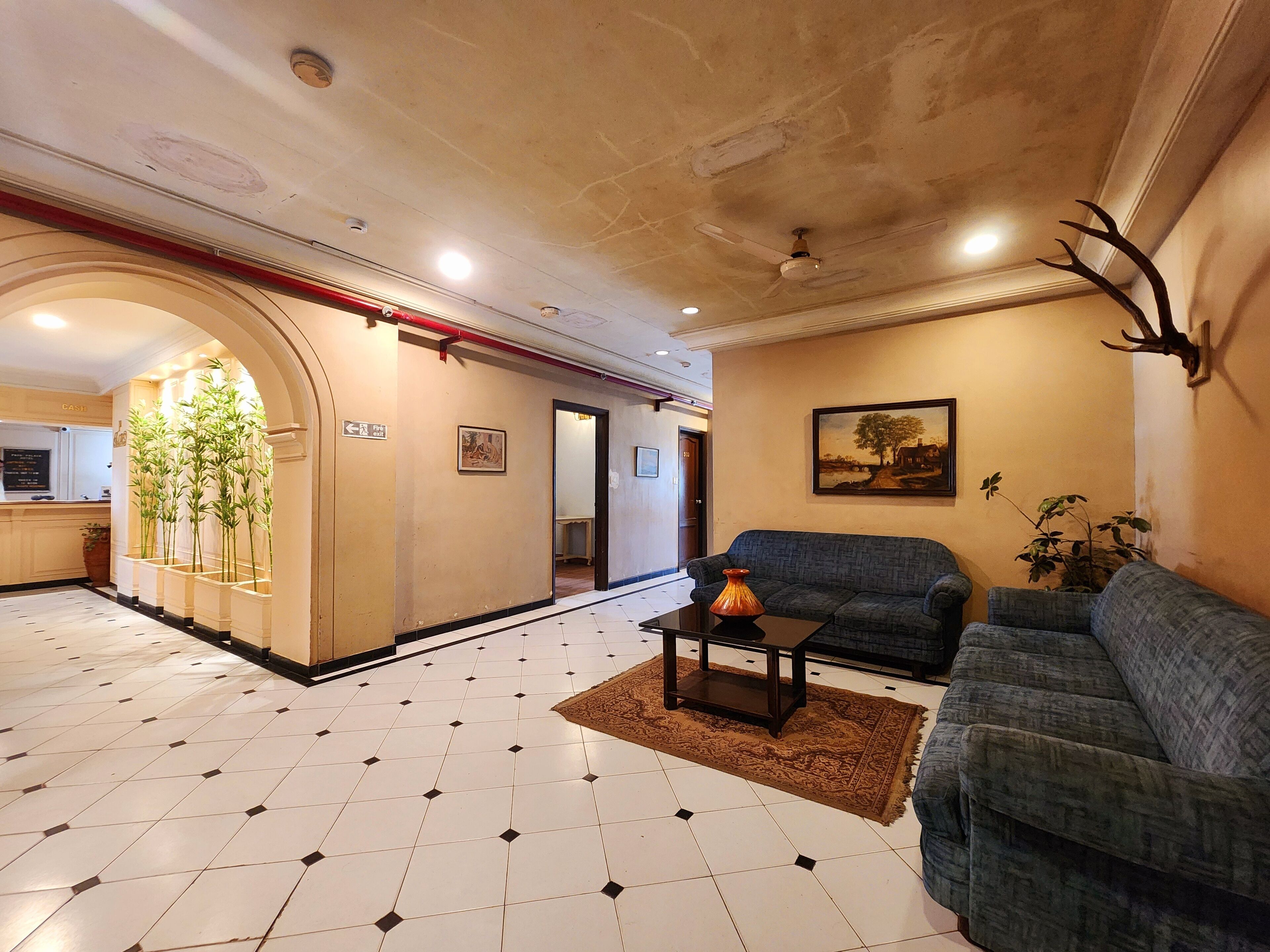A spacious lobby with a tiled floor, a sofa, a coffee table, and a wall-mounted deer head.