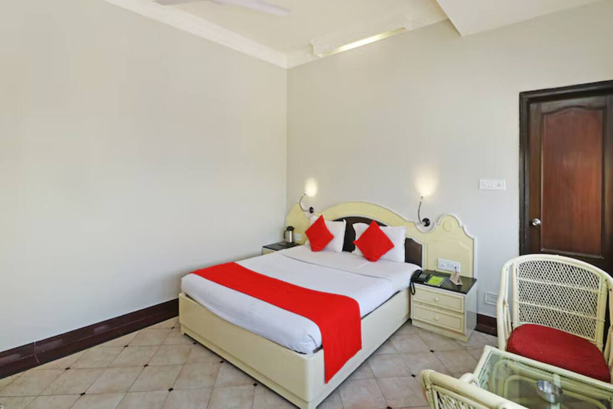 A bedroom with a bed, bedside tables, a chair, a door, and a ceiling fan.