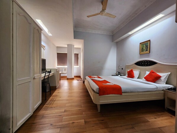 A bedroom with a bed, a desk, and a wardrobe.