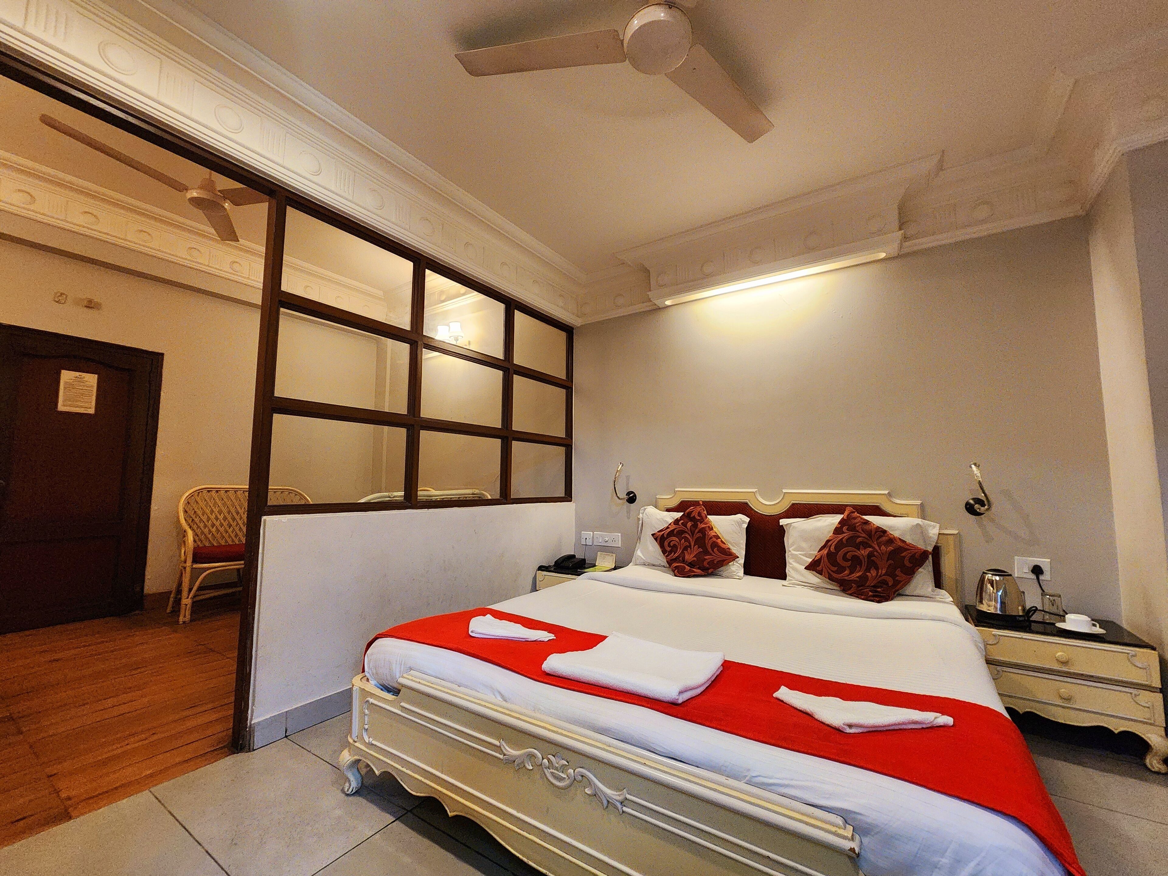 A hotel room with a bed, a nightstand, a chair, and a window.