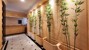 A hotel reception area with a tiled floor, a reception desk, and vertical planters with green plants.