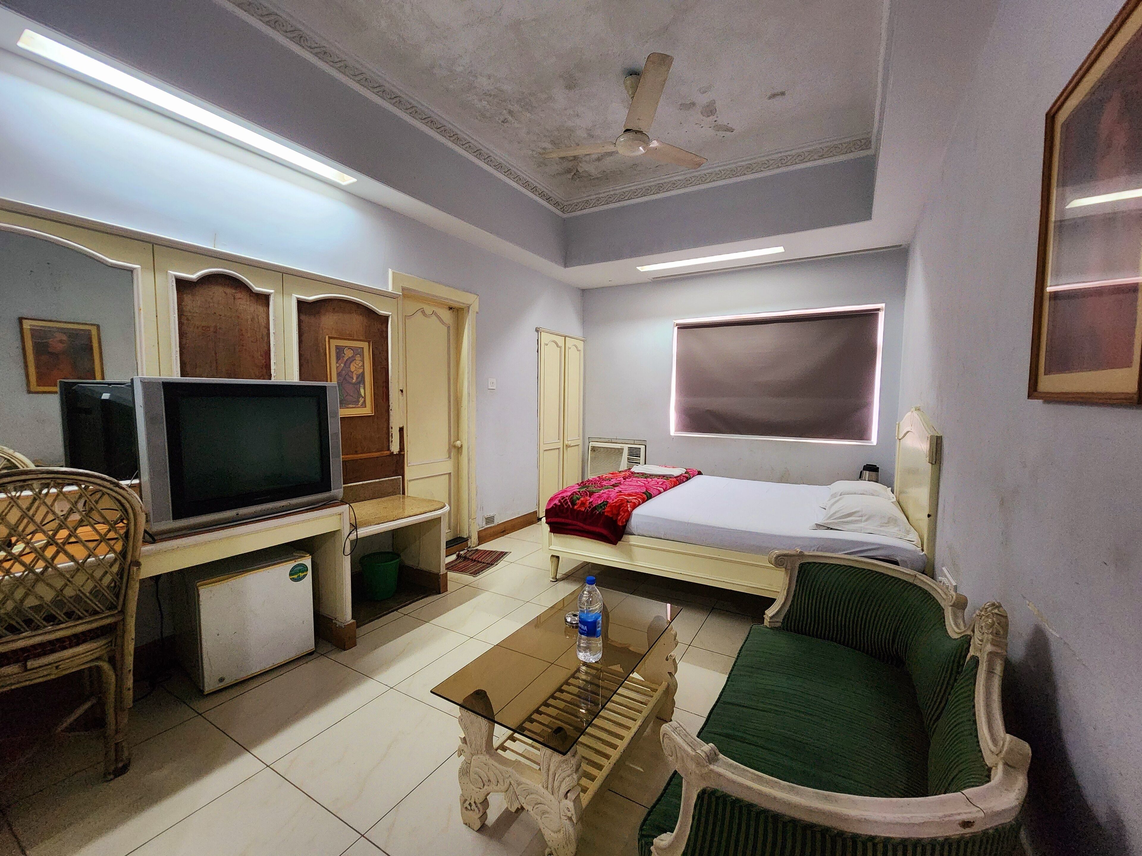 A room with a bed, a television, a table, and a chair.