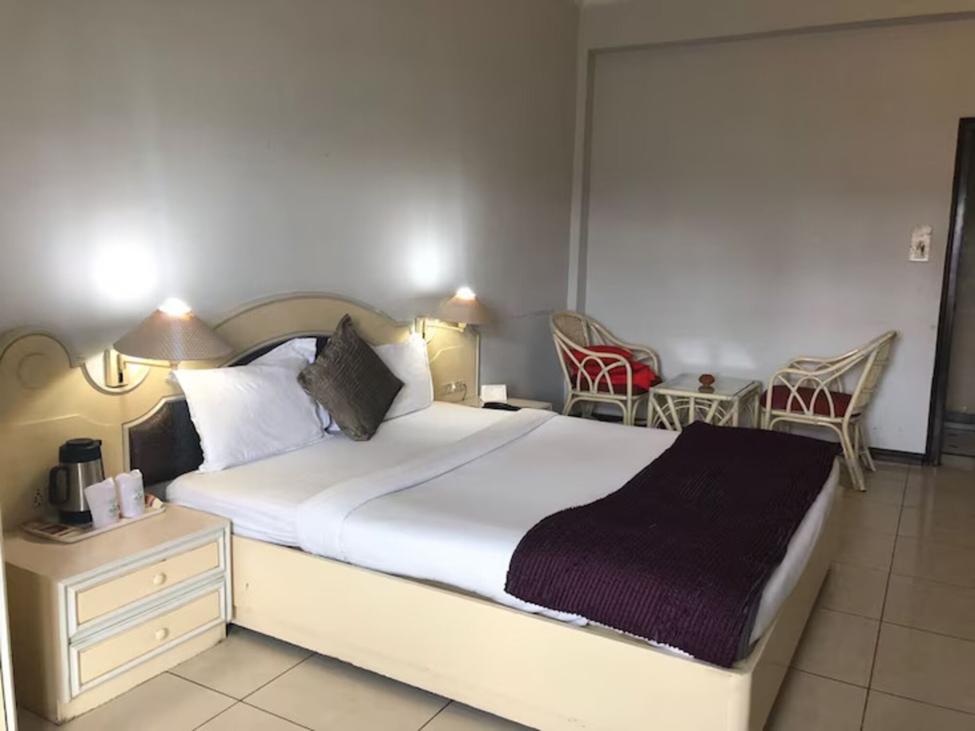 Une chambre d’hôtel avec un lit, des tables de chevet, une chaise et une lampe.