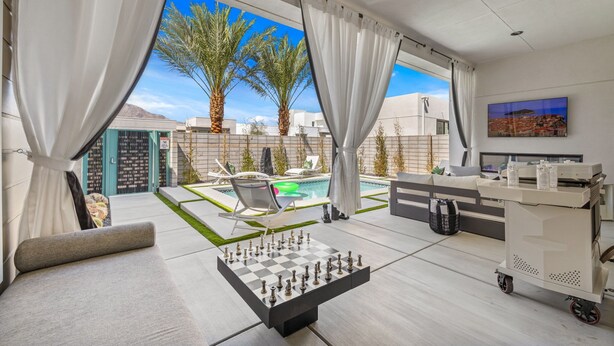 A modern living room with a chess table, a pool, and a TV. - Casa De Amore (Palm Springs)