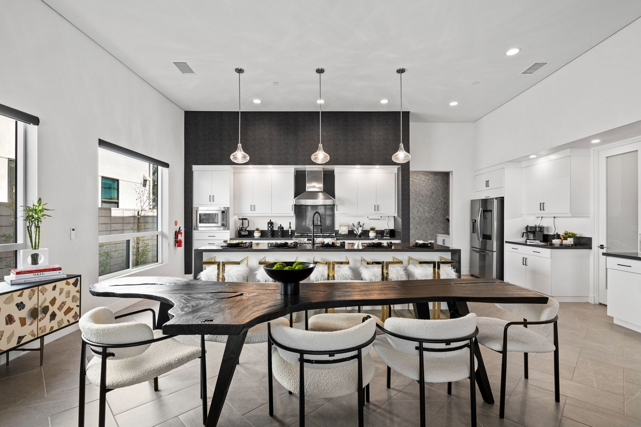 Une cuisine moderne dotée d’un îlot central, de luminaires suspendus et de meubles de couleur blanche.