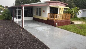 A single-story mobile home with a covered porch and a fenced deck area. - Lake Okeechobee Hideout - On the water (Moore Haven)