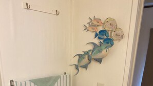 A bathroom with a striped towel, a wicker trash bin, and decorative fish wall art. - Lake Okeechobee Hideout - On the water (Moore Haven)