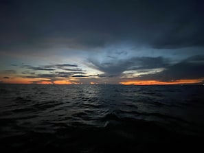 Une vue d’une plage au coucher du soleil, avec un ciel nuageux.