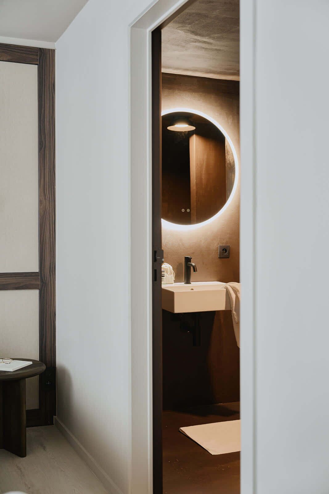 Une salle de bain moderne avec un miroir rond, un lavabo et une serviette accrochée au mur.